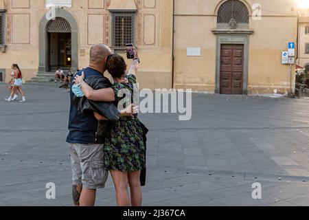 Pise, Italie - 9 août 2021: Un couple avec un smartphone prenant une photo d'eux-mêmes dans une place dans la vieille ville Banque D'Images