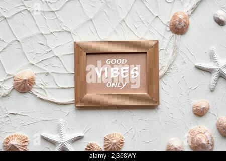 Texte bonne Vibes uniquement dans cadre doré. Sur fond blanc avec étoiles de mer, coquillages, coquillages, collier. Filet de pêcheur sur brun crème beige Banque D'Images