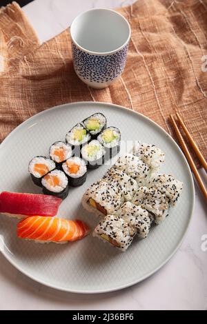 Mélange de sushis japonais traditionnels servi sur une assiette blanche. Banque D'Images