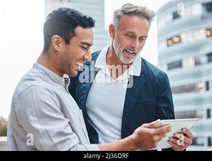 Le meilleur outil de collaboration sur le bloc. Photo de deux hommes d'affaires utilisant une tablette numérique dans un contexte urbain. Banque D'Images