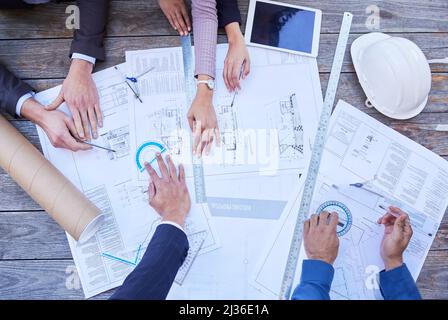 S'assurer de sa perfection. Photo en grand angle d'un groupe diversifié d'hommes d'affaires qui se sont réunis autour des plans de construction. Banque D'Images