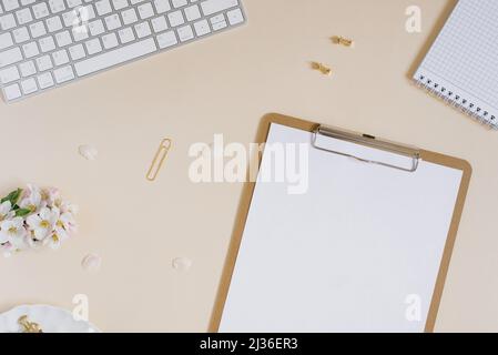 Papier vierge avec presse-papiers pour tablette avec espace de copie pour la copie. Magnifique bureau à la maison avec fleur de pomme fraîche, plateau en marbre, clavier, papier Banque D'Images