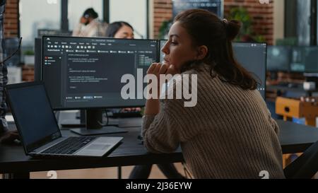 Développeur junior mettant un ordinateur portable avec code source sur le bureau de développement senior demandant l'opinion sur la base de données. L'algorithme d'écriture du programme est interrompu par un collègue qui souhaite obtenir de l'aide pour corriger les erreurs. Banque D'Images