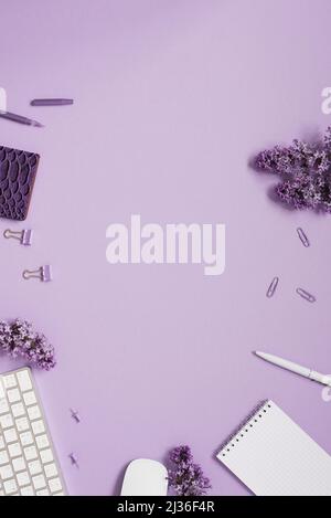 Blogger composition de printemps avec un carnet, papeterie, fleurs lilas et accessoires sur un fond violet. Ressort. Flat lay, vue de dessus. Banque D'Images