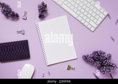 Clavier et souris, carnets, stylo, bouquet de lilas sur fond violet. Fleurs de printemps pourpres. Composition pour un blogueur. Ou entreprise Banque D'Images