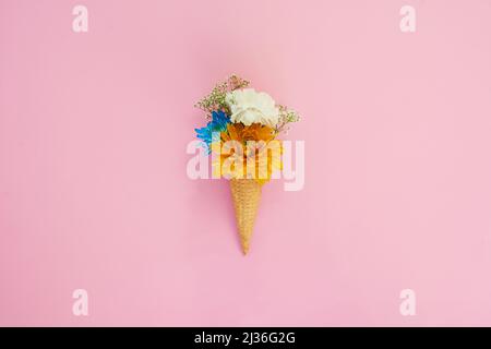 Tout est beau sur un cône de glace. Photo d'un cône rempli de fleurs sur un fond coloré. Banque D'Images