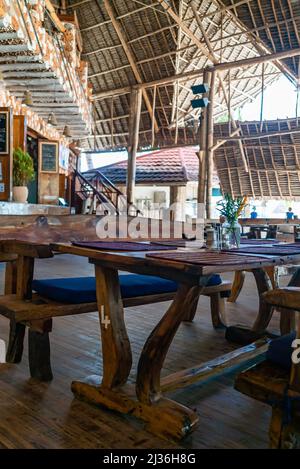 Tables en bois dans un café sous un toit.Intérieur authentique du restaurant à Kendwa, Zanzibar, Tanzanie. Banque D'Images