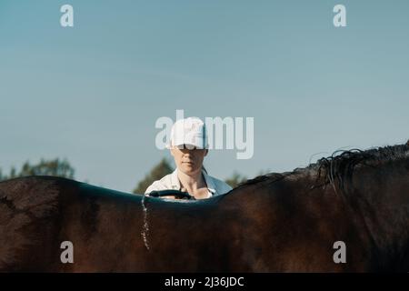 Femme, 40 ans, le cheval de lavage avec le tuyau à l'extérieur, gros plan. Banque D'Images