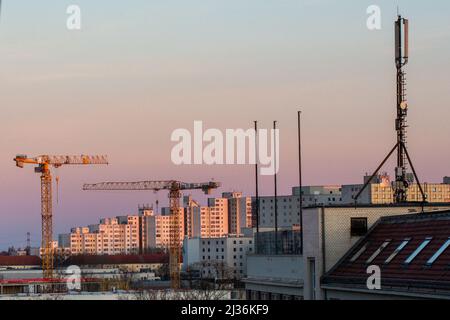 Berlin, Allemagne. 27th mars 2022. Les grues de construction brillent d'or à la lumière du soleil levant devant un domaine de logement. Credit: Fernando Gutierrez-Juarez/dpa-Zentralbild/dpa/Alay Live News Banque D'Images