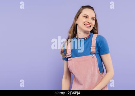 portrait de la femme joyeuse en robe générale souriante isolée sur le violet Banque D'Images