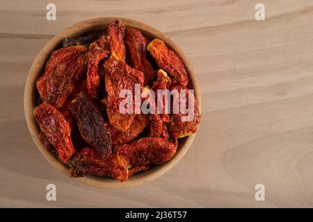 Bol de tomates séchées sur fond de bois, vue de dessus Banque D'Images