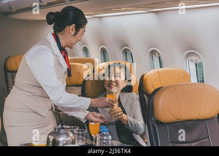 L'équipage de cabine d'hôtesse d'air sert des repas et des boissons aux passagers pendant le voyage à bord. Banque D'Images