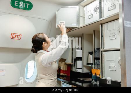 L'hôtesse de l'air prépare les aliments à l'aide d'un casier de sécurité dans la cabine de pilotage. Banque D'Images