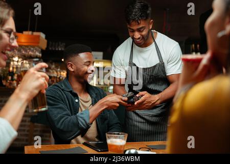 divers amis à l'extérieur pour dîner payant avec un appareil cellulaire Banque D'Images