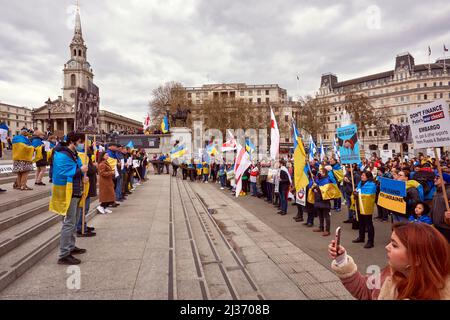 Une ligne de manifestants avec des affiches faisant face à la foule d'un côté et une affiche et des drapeaux de l'autre, Spire of St Martins in the Fields Behind Banque D'Images