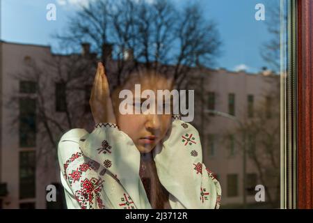 Une fille dans une robe brodée couvre ses oreilles avec ses mains afin de ne pas entendre les explosions. La jeune fille proteste contre la guerre, et montre patriotis Banque D'Images