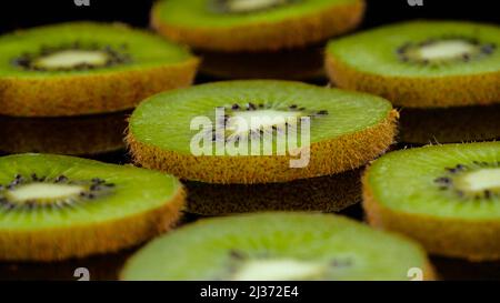 Tranches de kiwi sur fond noir dans. Gros plan de kiwi frais et savoureux, photo en studio. Banque D'Images