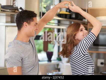 Ils ne manquent jamais une chance de danser. Photo d'un jeune couple heureux dansant dans leur cuisine à la maison. Banque D'Images