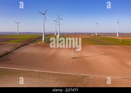 Un pôle de puissance et de nombreuses éoliennes énormes sur un champ vu d'en haut comme un tir de drone Banque D'Images