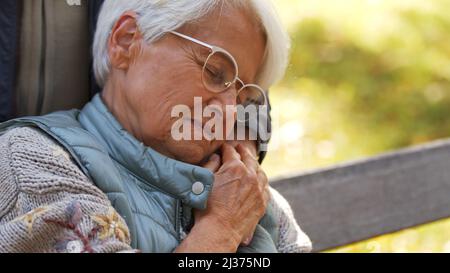 Portrait d'une femme caucasienne âgée avec des lunettes tenant la main de son mari et les yeux de fermeture copie espace parc arrière-plan . Photo de haute qualité Banque D'Images