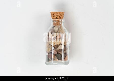 Petits rochers dans un flacon en verre avec bouchon en liège isolé sur fond blanc, pour souvenir, pierres de sable cassées dans un flacon en verre, permettant de gagner de la mémoire sur le bol, Banque D'Images