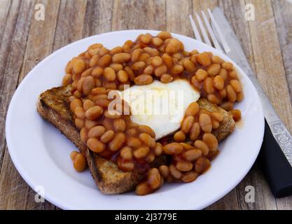 Un œuf frit et des haricots cuits dans de la sauce tomate sur du pain grillé Banque D'Images