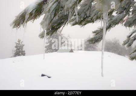 Focus sur un glaçon, sur fond vue floue du camping sauvage d'hiver dans Etna Park, Sicile Banque D'Images