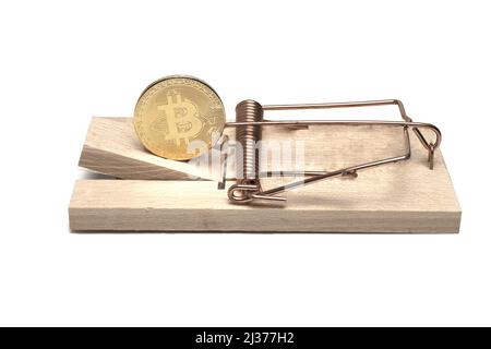 Gros plan d'une pièce de monnaie en bitcoin utilisée comme leurre dans un piège à rat en bois massif de mousetrap dangereusement coké avec ressort en cuivre et fermoir sur fond blanc c Banque D'Images