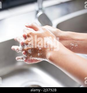 Je me lave les mains à la minute où je pénètre dans la maison. Coupe courte d'une femme méconnaissable se lavant les mains dans le lavabo à la maison. Banque D'Images