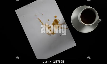 Papier contenant du café renversé, café filtre sur table noire, tasse blanche et dessous de verre, isolé sur fond noir, vue du dessus Banque D'Images
