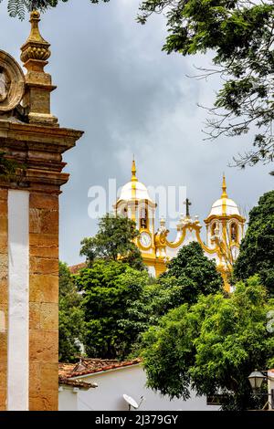 Tour d'église et vieux bâtiments parmi la végétation de la ville historique de Tiradentes dans l'état de Minas Gerais, Brésil Banque D'Images