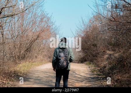 Homme errant sur un chemin avec un sac à dos dans une forêt, un homme avec sac marchant sur une route dans la nature Banque D'Images