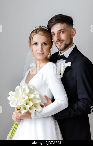 Une jolie mariée habille une mariée dans une robe de mariée. Les jeunes mariés s'embrassent dans la chambre et passent du temps ensemble Banque D'Images