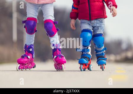 Enfants garçon et fille s'amuser à l'extérieur tout en faisant des patins à roulettes. Enfants sur les rollers. Patinage à roulettes dans le parc près de la mer. Banque D'Images