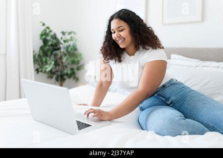 fille utilisant un ordinateur portable dans le lit pendant la matinée à la maison Banque D'Images