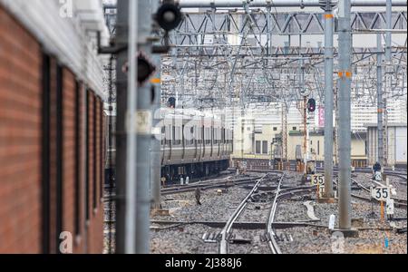 Le train quitte la gare après des rails vides et une masse de câblage aérien Banque D'Images