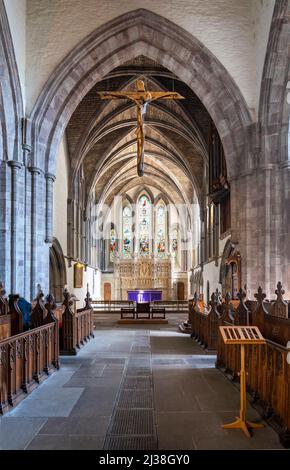 Le crucifix en bois sculpté accroché au plafond de la cathédrale, au-dessus de l'île principale et sol carrelé en pierre, avant les grandes arches, vitraux winpo Banque D'Images