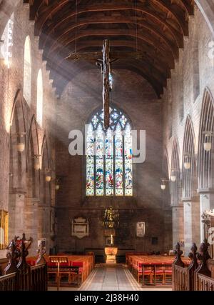 Le crucifix en bois sculpté accroché au plafond de la cathédrale, au-dessus de l'île principale et sol carrelé en pierre, avant les grandes arches, vitraux winpo Banque D'Images