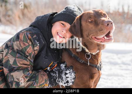 Portrait d'un petit garçon avec un chien du labrador en hiver Banque D'Images