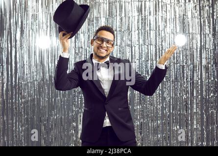 Joyeux homme souriant dans un chapeau haut et un smoking avec un noeud papillon s'amusant à une fête Banque D'Images