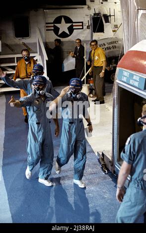 Les membres d'équipage de l'USS Hornet sont accueillis par l'équipage de la mission d'atterrissage lunaire Apollo 12 alors que les trois astronautes sont transférés d'un hélicoptère de la Marine américaine à une installation de quarantaine mobile (FQS) à bord du navire de récupération de premier plan. Charles Conrad Jr., à droite, commandant; Richard F. Gordon Jr., pilote du module de commande, à gauche, et Alan L. Bean, pilote du module lunaire, ont été éclatés en toute sécurité à 2 h 58pm, le 24 novembre 1969. Crédit: NASA via CNP Banque D'Images