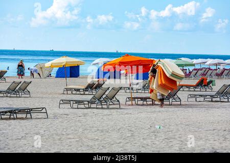 MIAMI, USA - JUL 31, 2010: Les gens quittent la plage à Miami en fin d'après-midi et le garçon de plage récupère les matelas des canapés de plage à Miami. Banque D'Images