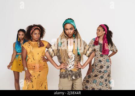 Jeunes quatre femmes noires portant une robe se posant ensemble sur un appareil photo isolé sur fond blanc Banque D'Images