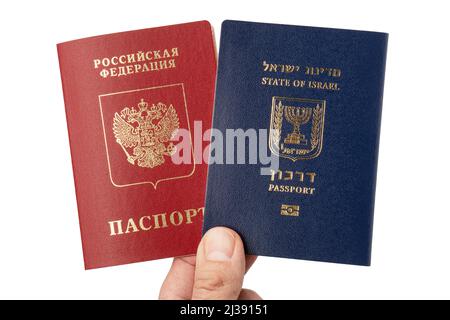 La main masculine tient les passeports de voyage internationaux israéliens et russes isolés sur fond blanc. Banque D'Images