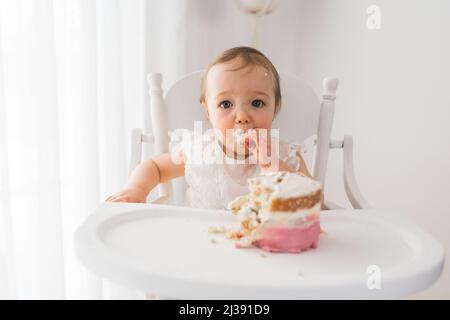 Le gâteau du premier anniversaire d'une petite fille s'assoit sur une chaise Banque D'Images