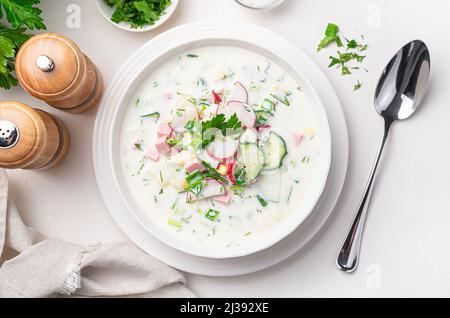 Soupe froide de légumes okroshka sur fond blanc. Vue de dessus, gros plan. Banque D'Images