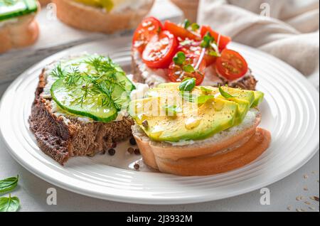 Sandwiches avec feta, avocat, tomates, concombre et herbes fraîches sur un fond léger gros plan. Des collations saines. Banque D'Images