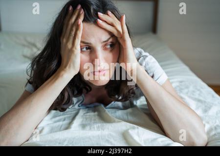 Triste, malheureux femme couché sur le lit dans la dépression. Maux de tête, stress, anxiété, tension, problèmes psychologiques. Mauvaise santé mentale, psychologue visiteur, psycho Banque D'Images