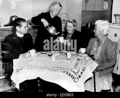 Le directeur de Hammondville le rév. Bernard Judd apprécie une tasse de thé avec Mme Daniel Lane, Mme C. Wright et Mme James Gilman dans la salle de séjour de Mme Lane lors d'une de ses visites bimensuelles au village. 01 février 1955. Banque D'Images