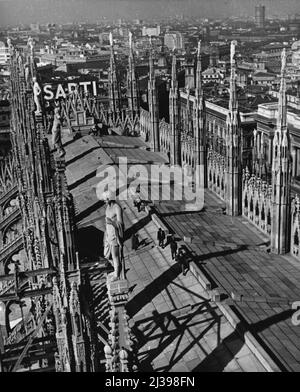 La Forêt pétrifiée de Milan -- le toit de la cathédrale de Milan apparaît comme une avenue bordée de flèches semblables à des arbres, qui soutiennent toutes des statues des saints. La ville, qui possède les seuls gratte-ciels italiens, s'étend en dessous. 22 octobre 1954. (Photo de United Press). Banque D'Images